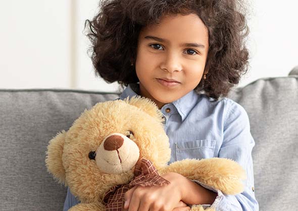 Little girl holding a teddy bear.