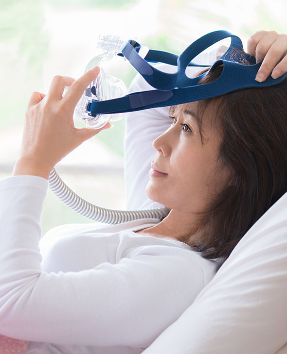Woman putting on a mask for sleep apnea.